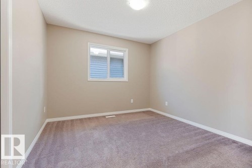 Room featuring neutral wall paint, white trim, textured ceiling, flush-mount lighting, and a double-pane window - 1306 32A Street, Edmonton, AB 