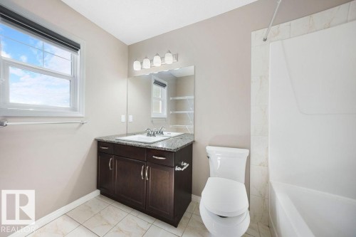 Bathroom featuring a dark wood vanity with a granite countertop, undermount sink, and polished chrome faucet - 1306 32A Street, Edmonton, AB 