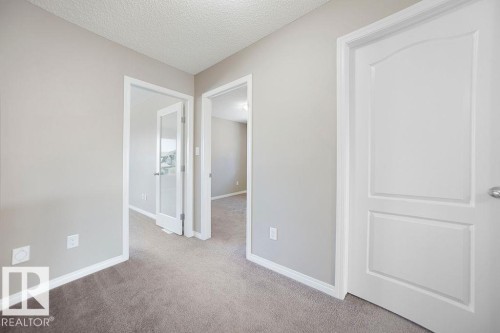 Hallway featuring soft gray wall paint, crisp white baseboards, and neutral-toned carpeting - 1306 32A Street, Edmonton, AB 