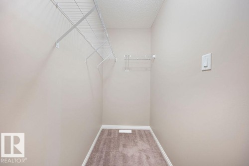 Walk-in closet featuring wire shelving, wall-mounted light switch, neutral wall paint, white baseboards, and carpet flooring - 1306 32A Street, Edmonton, AB 