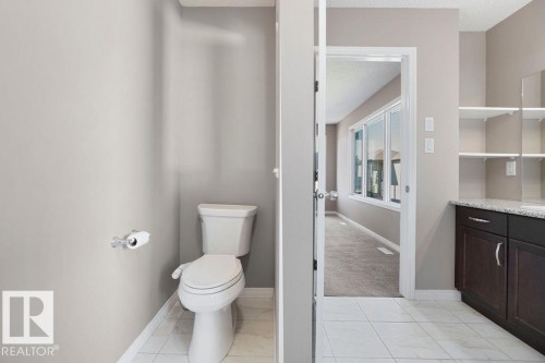 Bathroom featuring a white toilet, light-toned wall paint, and ceramic tile flooring - 1306 32A Street, Edmonton, AB 