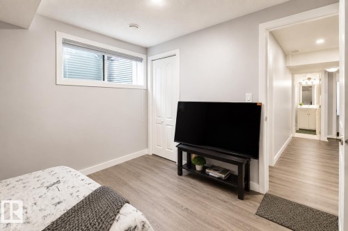 Bright room with light gray walls, wood-finish flooring, a window with horizontal blinds, and a bi-fold closet door - 1306 32A Street, Edmonton, AB 