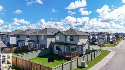 Two-story residential property featuring a rear wooden deck, fenced yard with green lawn, and a sidewalk-fronted corner lot - 1306 32A Street, Edmonton, AB 