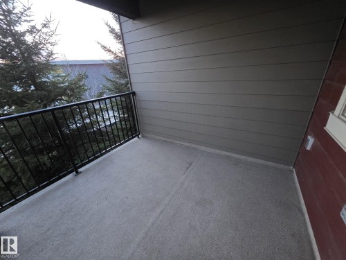 Private balcony featuring textured concrete flooring, black metal railings, and horizontal siding - 310 12045 22 Avenue, Edmonton, AB 