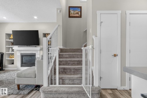 Central staircase with carpeted treads and white railings - 2534 Wonnacott Loop, Edmonton, AB 