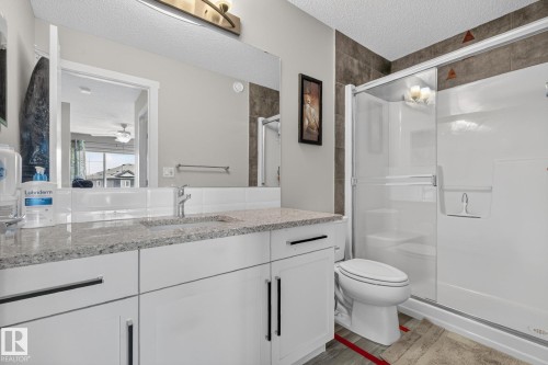 Bathroom featuring a white vanity with a light-toned countertop, a shower enclosure with a sliding glass door, and a white toilet - 2534 Wonnacott Loop, Edmonton, AB 