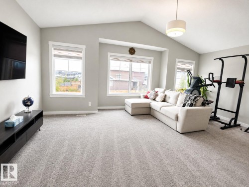 Spacious room featuring vaulted ceilings, light gray wall paint, and plush gray carpet flooring - 2534 Wonnacott Loop, Edmonton, AB 