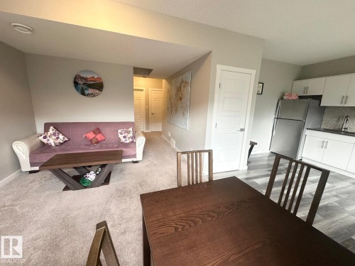 Open-concept living space featuring a kitchen with white cabinetry and a stainless steel refrigerator - 2534 Wonnacott Loop, Edmonton, AB 