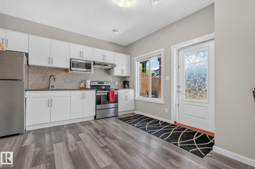 Modern kitchen featuring white cabinetry, stainless steel appliances, and a mosaic tile backsplash - 2534 Wonnacott Loop, Edmonton, AB 