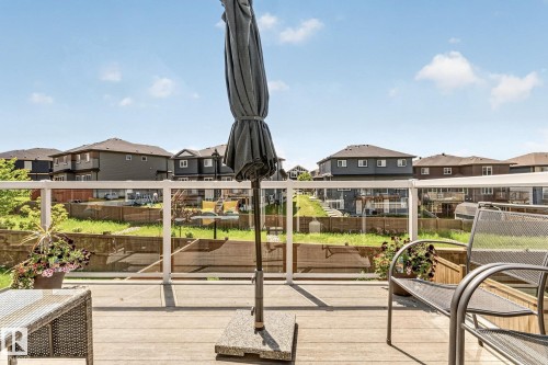 Outdoor deck with wood-finish flooring, glass panel railing, and neighborhood backdrop - 2534 Wonnacott Loop, Edmonton, AB 