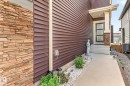 Front entry with durable concrete walkway, a covered porch, and layered stone accents - 2534 Wonnacott Loop, Edmonton, AB 