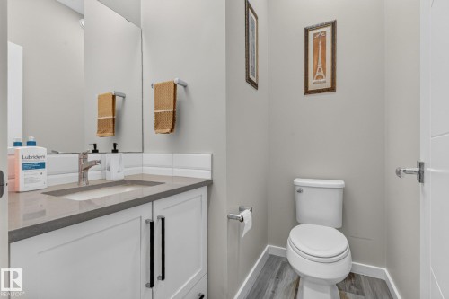 Vanity with a light gray countertop, white cabinetry with black hardware, and an integrated rectangular sink - 2534 Wonnacott Loop, Edmonton, AB 