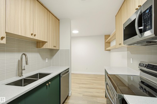 Contemporary kitchen featuring light wood-finish upper cabinetry, contrasting deep green lower cabinetry, and stainless steel appliances - 18217 84 Avenue Nw, Edmonton, AB 