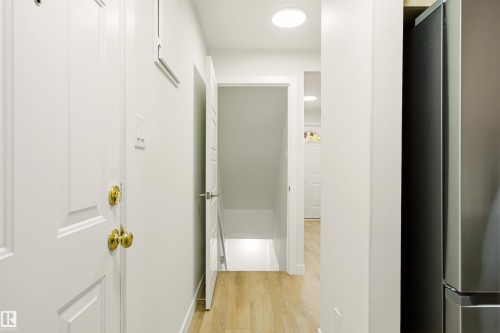 Hallway featuring light wood-finish flooring, recessed ceiling lighting, and crisp white walls - 18217 84 Avenue Nw, Edmonton, AB 