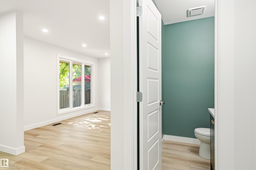 Bright interior space with wood-finish flooring, recessed lighting, and a large multi-pane window - 18217 84 Avenue Nw, Edmonton, AB 