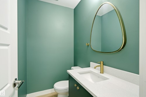 Powder room featuring a sleek vanity with an integrated sink, a white stone-finish countertop, and a modern gold-toned faucet - 18217 84 Avenue Nw, Edmonton, AB 