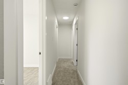 Interior hallway featuring light-toned carpeting, white walls, and recessed lighting - 