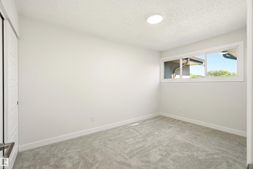 Room featuring light gray carpet, white walls, and a large window with white trim - 18217 84 Avenue Nw, Edmonton, AB 