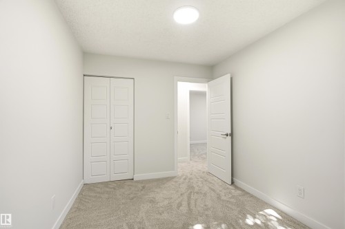 Neutral-toned carpeting paired with white walls, a white ceiling, and a flush-mount overhead light fixture - 18217 84 Avenue Nw, Edmonton, AB 