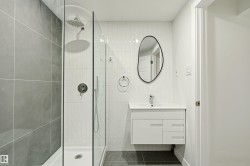 Contemporary bathroom featuring a frameless glass shower enclosure, a rainfall showerhead, and a wall-mounted vanity with integrated sink - 