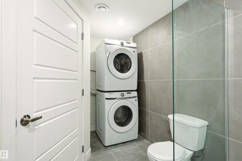 Compact laundry area with stacked washer and dryer units - 18217 84 Avenue Nw, Edmonton, AB 
