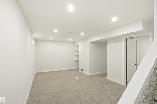 Spacious room featuring plush gray carpeting, recessed lighting, white walls, and built-in shelving - 18217 84 Avenue Nw, Edmonton, AB 