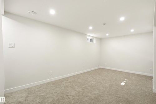 Spacious room featuring new carpeting, recessed ceiling lighting, a light-colored window, white walls, and white baseboards - 18217 84 Avenue Nw, Edmonton, AB 