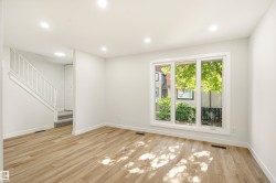 Bright living space featuring wood-finish flooring, recessed lighting, and a large multi-pane window - 