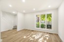 Bright living space featuring wood-finish flooring, recessed lighting, and a large multi-pane window - 18217 84 Avenue Nw, Edmonton, AB 
