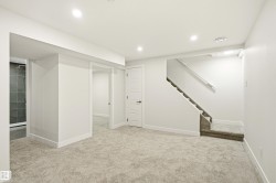 Spacious lower-level area featuring plush carpeting, recessed lighting, white trim, and a fully tiled shower enclosure - 