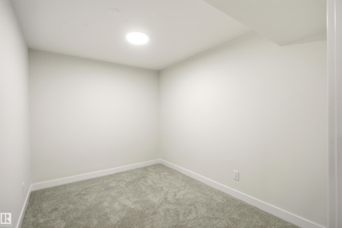 Neutral-toned room featuring a recessed circular light fixture, light gray carpeting, white walls, and clean white baseboards - 18217 84 Avenue Nw, Edmonton, AB 