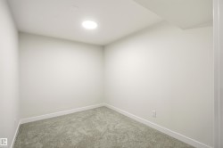 Neutral-toned room featuring a recessed circular light fixture, light gray carpeting, white walls, and clean white baseboards - 