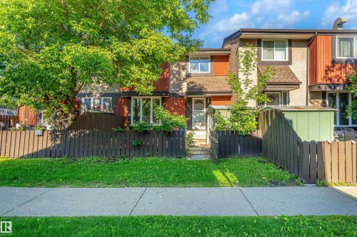 Townhome exterior with a partial brown picket fence and concrete walkway - 18217 84 Avenue Nw, Edmonton, AB 