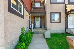 Stucco exterior with brown trim accents, concrete walkway, and covered entryway - 