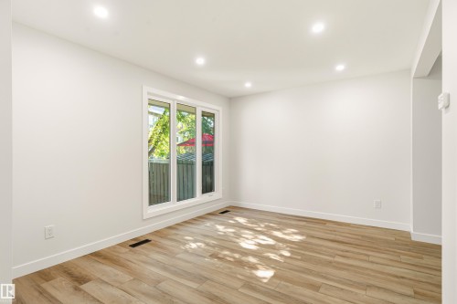 Bright interior space featuring wood-finish flooring, recessed lighting, and a large multi-pane window - 18217 84 Avenue Nw, Edmonton, AB 