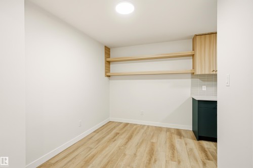 Kitchenette featuring light wood-finish open shelving, upper cabinetry, and a dark green lower cabinet with a light countertop - 18217 84 Avenue Nw, Edmonton, AB 