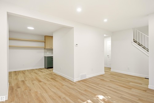 Open concept living area featuring wood-finish flooring, recessed lighting, and a built-in wet bar with a countertop, cabinetry, and open shelving - 18217 84 Avenue Nw, Edmonton, AB 