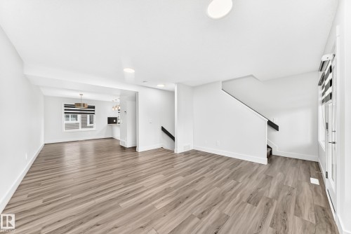 Spacious open-concept interior featuring light wood-finish flooring and crisp white walls - 17 4137 76 Street, Edmonton, AB 