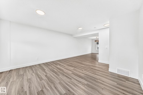 Expansive interior space featuring wood-finish flooring, recessed lighting, crisp white walls, and bright white baseboards - 17 4137 76 Street, Edmonton, AB 