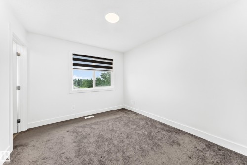 Carpeted room featuring a window with horizontal blinds, white walls, and a ceiling-mounted light fixture - 17 4137 76 Street, Edmonton, AB 