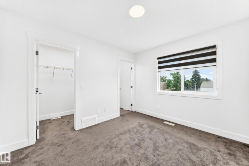 Carpeted room with white walls, featuring a window with a two-tone roller shade, recessed lighting, and a closet with wire shelving - 17 4137 76 Street, Edmonton, AB 