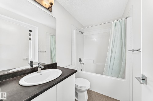 Bathroom featuring a vanity with dark countertop and oval undermount sink, alongside a full bathtub with shower - 17 4137 76 Street, Edmonton, AB 