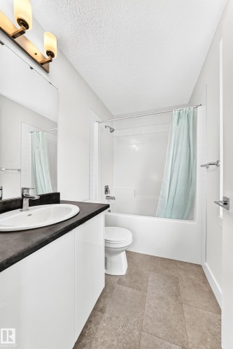 Bathroom featuring a white vanity with a dark countertop, an undermount sink, and a chrome faucet - 17 4137 76 Street, Edmonton, AB 