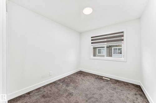 Bright room featuring a single window with blinds, recessed ceiling lighting, and dark grey carpeting - 17 4137 76 Street, Edmonton, AB 