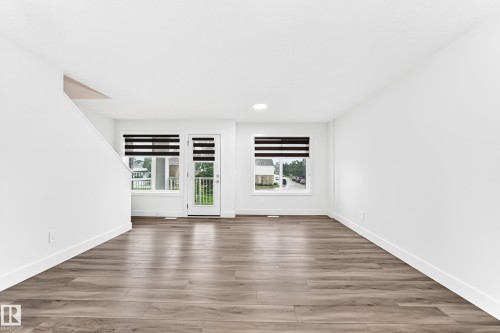 Spacious room with wood-finish flooring, white walls, and bright overhead lighting - 17 4137 76 Street, Edmonton, AB 