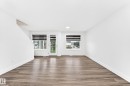 Spacious room with wood-finish flooring, white walls, and bright overhead lighting - 17 4137 76 Street, Edmonton, AB 