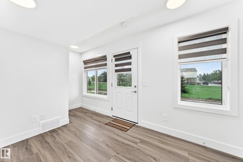 Entryway featuring wood-finish flooring, white walls, and a white door with two adjacent windows - 17 4137 76 Street, Edmonton, AB 