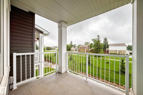 Covered balcony featuring a textured concrete floor, white railing, and white ceiling - 17 4137 76 Street, Edmonton, AB 
