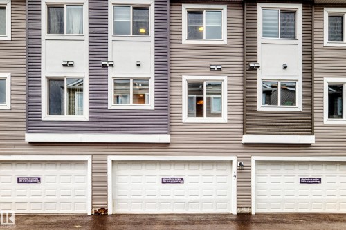 Exterior facade featuring horizontal siding in varied tones, white framed windows, and integrated wall sconces - 17 4137 76 Street, Edmonton, AB 