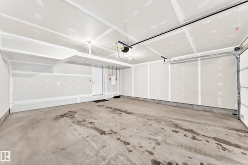 Spacious garage featuring a concrete floor, overhead lighting, and an automatic garage door opener - 17 4137 76 Street, Edmonton, AB 